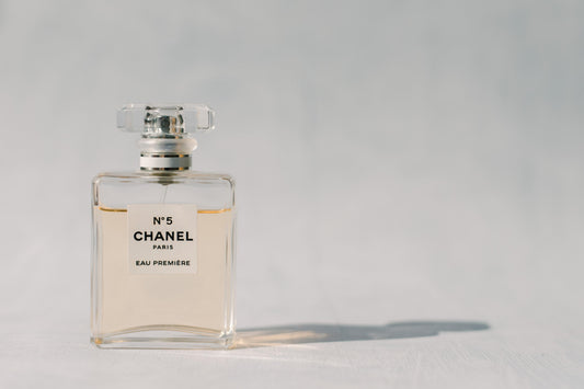 A bottle of Number 5 Chanel Paris perfume sitting on a plain grey backdrop.